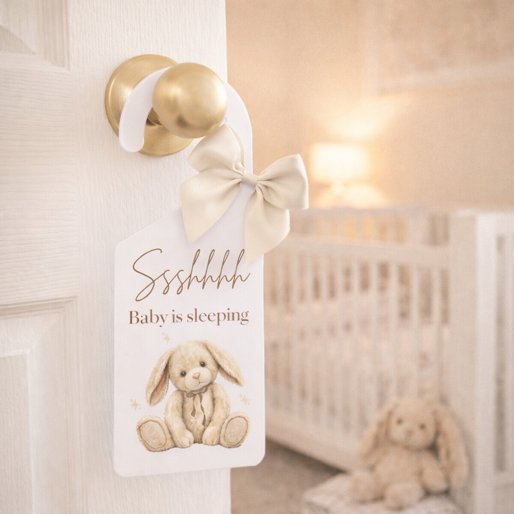 Door hanger with a bunny illustration and 'Baby is sleeping' text in a nursery setting.