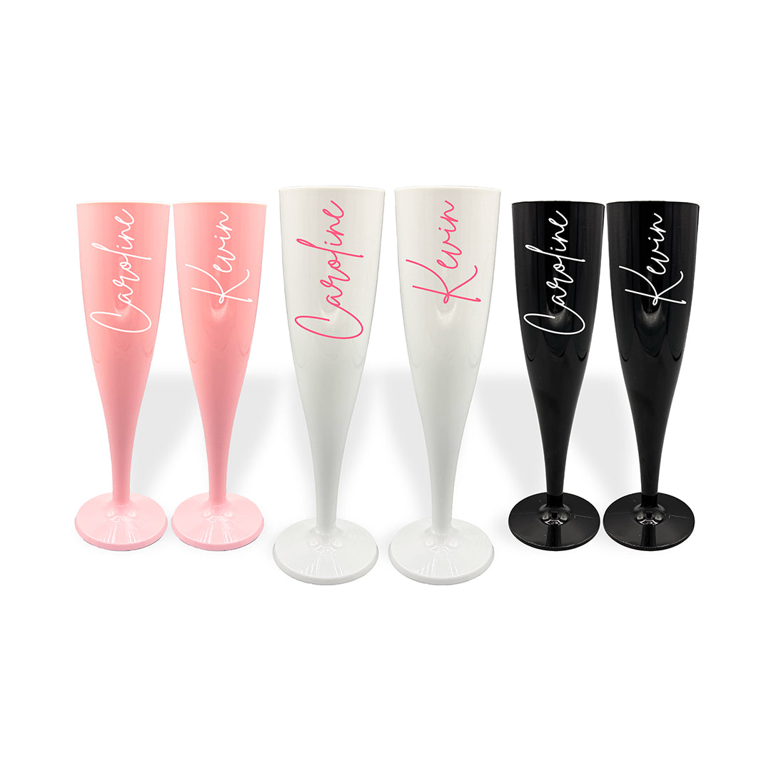 Three pairs of plastic champagne flutes, in pink, white and black. All decorated with a signature font and personalised with names