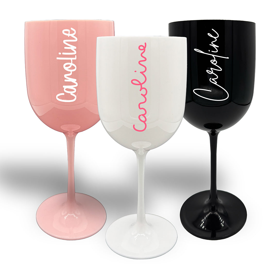 Three large plastic wine glasses in pink, white and black. Each decorated with the name Caroline in different style fonts