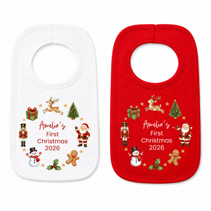 Two baby bibs shown side by side on a white background: one white bib with a multicolor Christmas print and the text 'Amelia's First Christmas 2026', and one red bib with the same print.