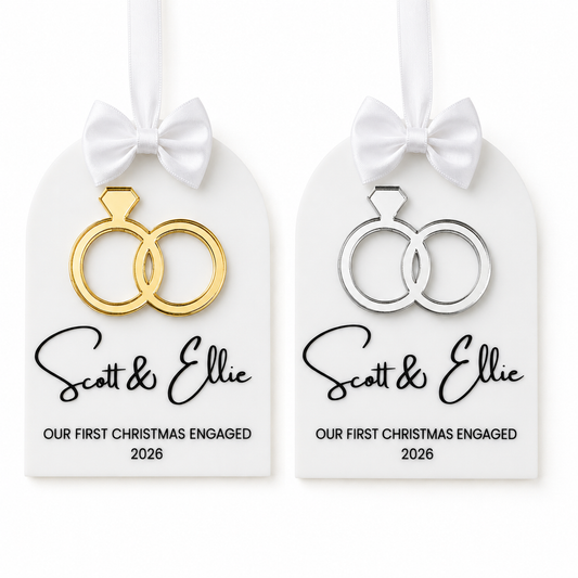 Two personalized Christmas ornament tags on a white background, each with a white ribbon bow. One tag has gold ring cutouts and the other has silver ring cutouts.