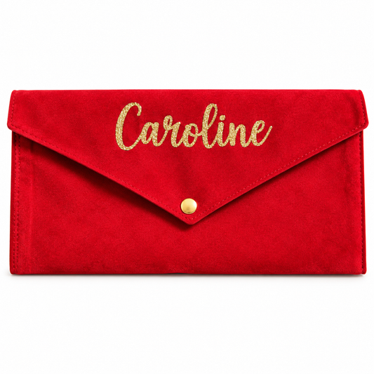A red suede envelope clutch bag with 'Caroline' written in gold glitter script on the flap and a small gold snap button, shown on a plain white background.