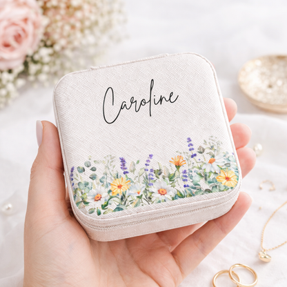Hand holding a small white jewelry case with floral design and 'Caroline' branding.
