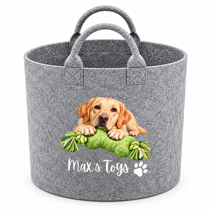 A gray felt pet toy basket with two handles, featuring a printed graphic of a golden retriever puppy playing with a green rope toy and the text 'Max's Toys' with a paw print.