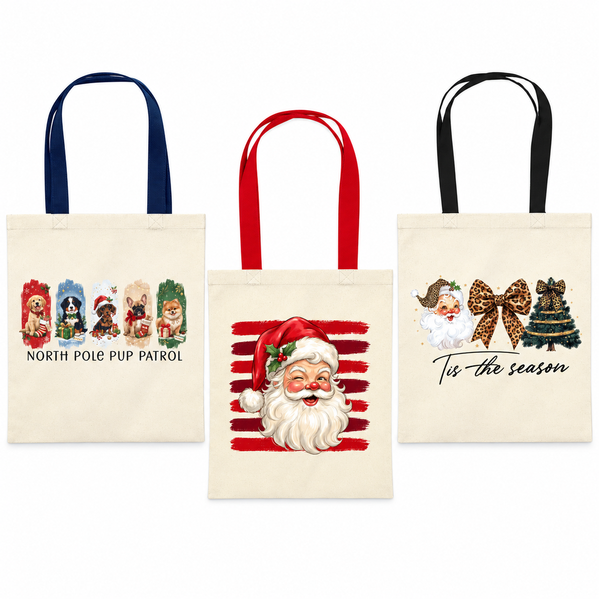Three canvas tote bags with holiday-themed prints on a white background. The left bag has navy blue handles and a 'North Pole Pup Patrol' graphic.