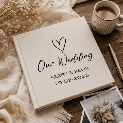 Wedding album with 'Our Wedding' inscription and a cup of coffee on a wooden surface.