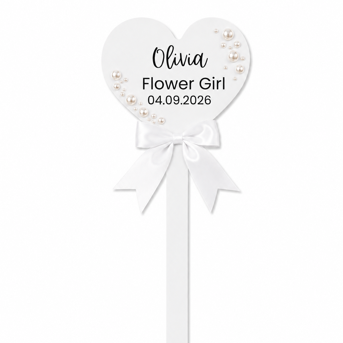 A personalized white heart-shaped flower girl wand with a white ribbon bow, pearl embellishments, and custom text reading 'Olivia Flower Girl 04.09.