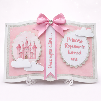 Decorative book with pink ribbon, castle illustration, and text on a white background