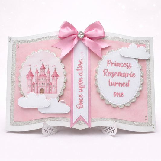 Decorative book with pink ribbon, castle illustration, and text on a white background