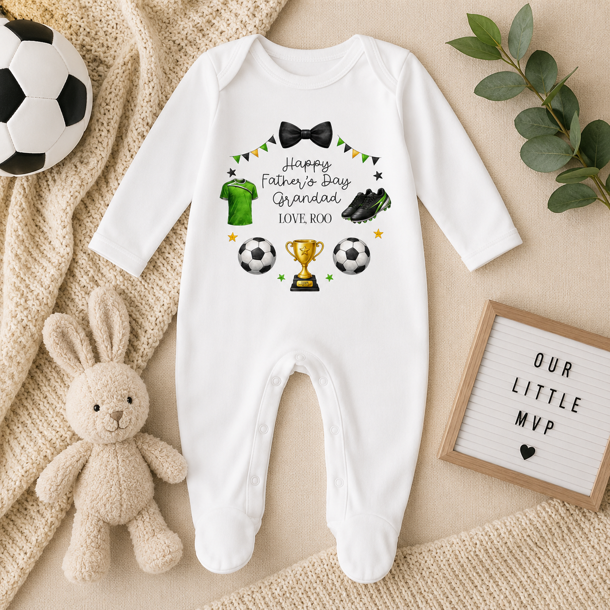 White baby onesie with Father's Day design on a beige surface with toys and decor.