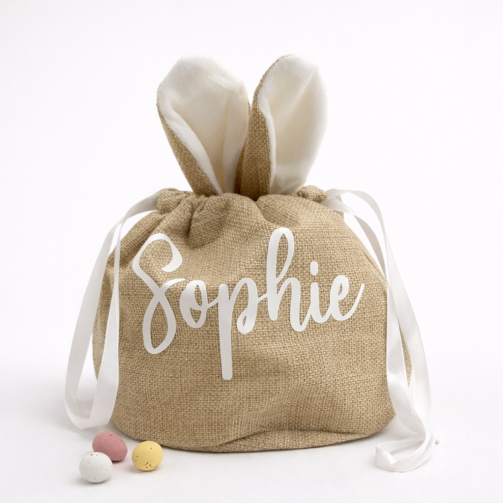 Burlap bag with bunny ears and 'Sophie' personalised on it, with Easter eggs on a white background.