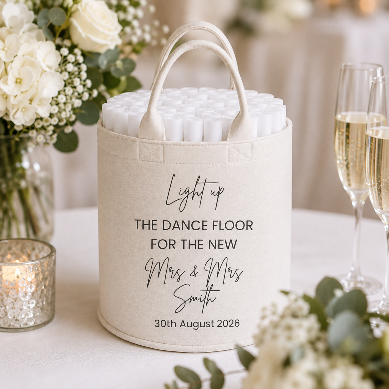 A personalized white fabric dance floor light holder with two top handles, filled with white cylindrical lights. The fabric holder is printed with black text reading 'Light up THE DANCE FLOOR FOR THE NEW Mrs & Mrs Smith 30th August 2026'.