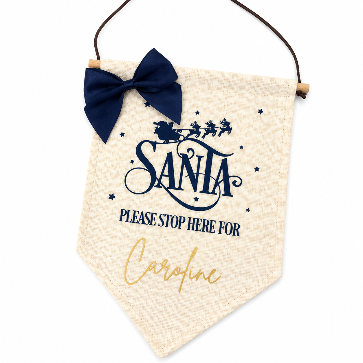 Decorative sign with 'Santa Please Stop Here' text and a navy bow on a white background
