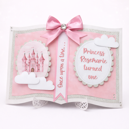 Decorative book with pink ribbon, castle illustration, and text on a white background