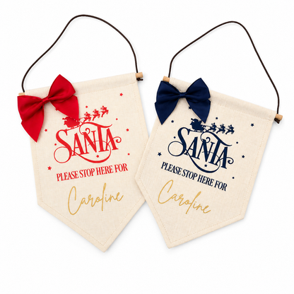 Two decorative signs with 'Santa Please Stop Here' text and red and blue bows on a white background.